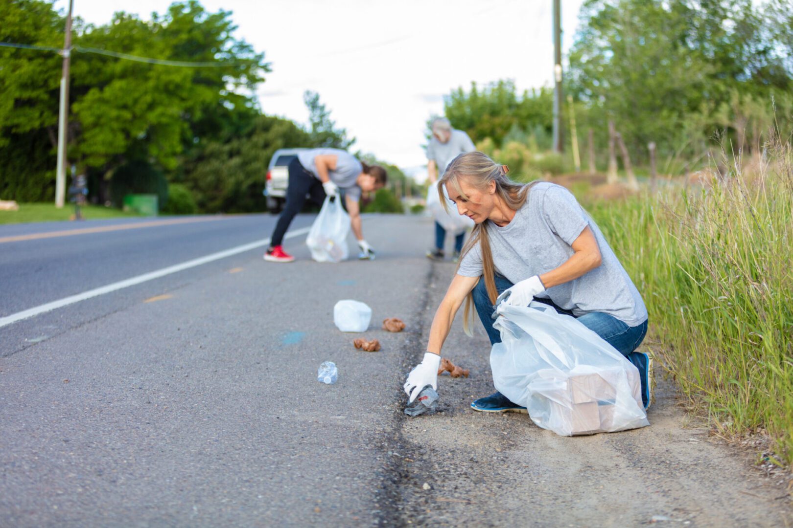 Volunteers picking up trash along a roadside.