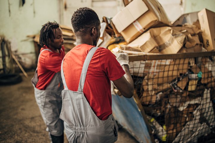 Two workers sorting recyclable materials in a facility.