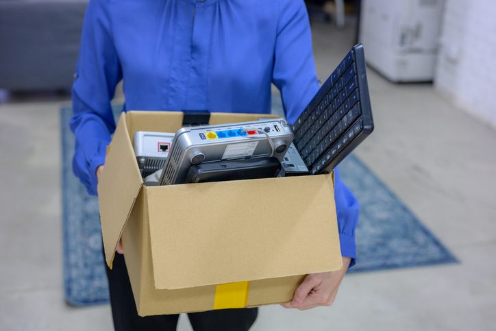 Person holding a cardboard box filled with packed items.